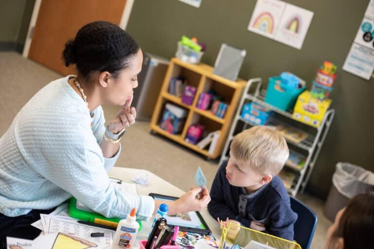 Speech-language pathologist working with a student in a school setting, illustrating the transition from a clinical role to a school-based SLP position.